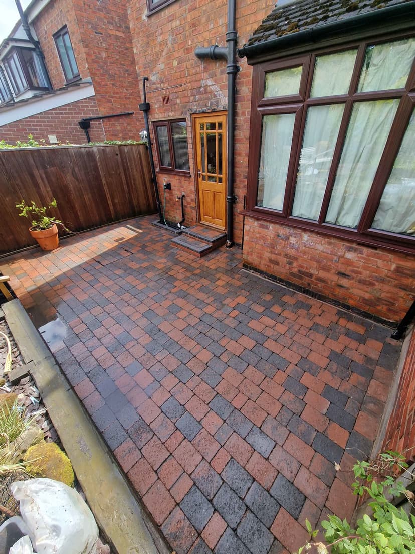 Block-paved courtyard after — moss gone, the red and charcoal blocks back to full colour.