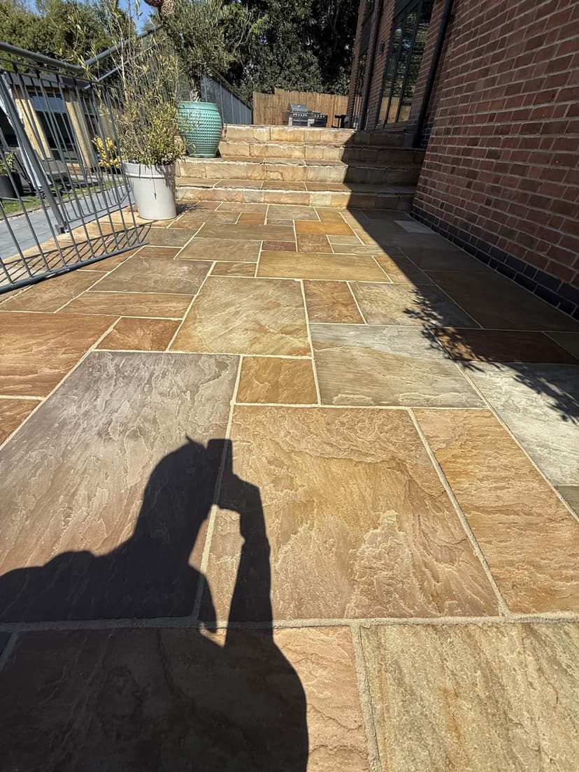 Indian sandstone patio glowing after a full clean — the natural golds and ambers restored.
